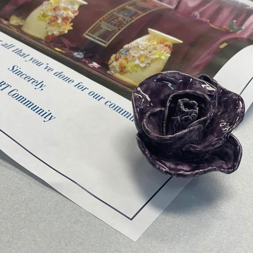  a close up of a ceramic flower, painted purple, sitting on the table